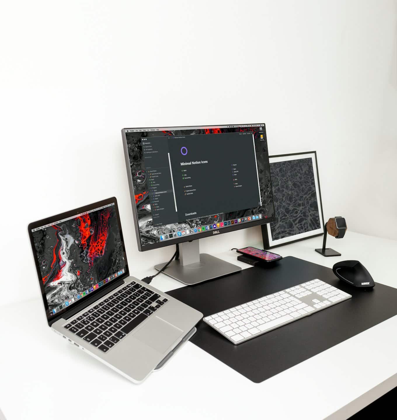 Home Spazio di lavoro minimalista con laptop, monitor e accessori da scrivania su una scrivania bianca.